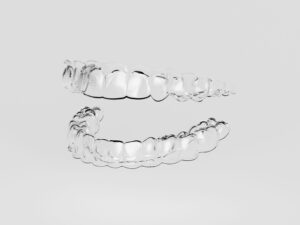 A set of clear aligners barely visible on an off-white background
