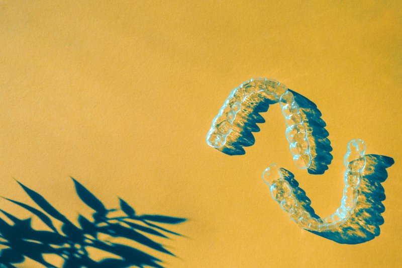A pair of clear aligners on a yellow background